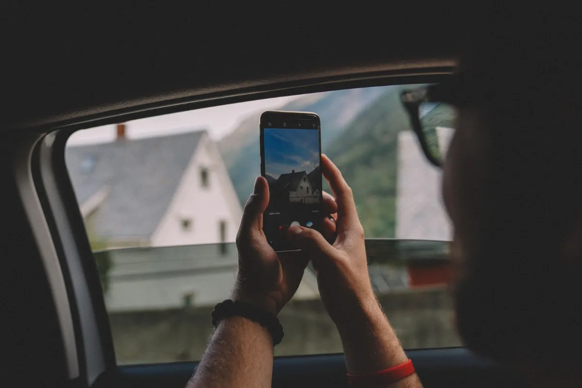 A technician in a branded shirt photographing a finished install on his phone with the company truck behind him