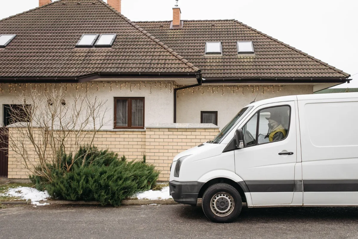 A neighborhood driveway with a clean branded work truck parked in it and a matching yard sign at the curb