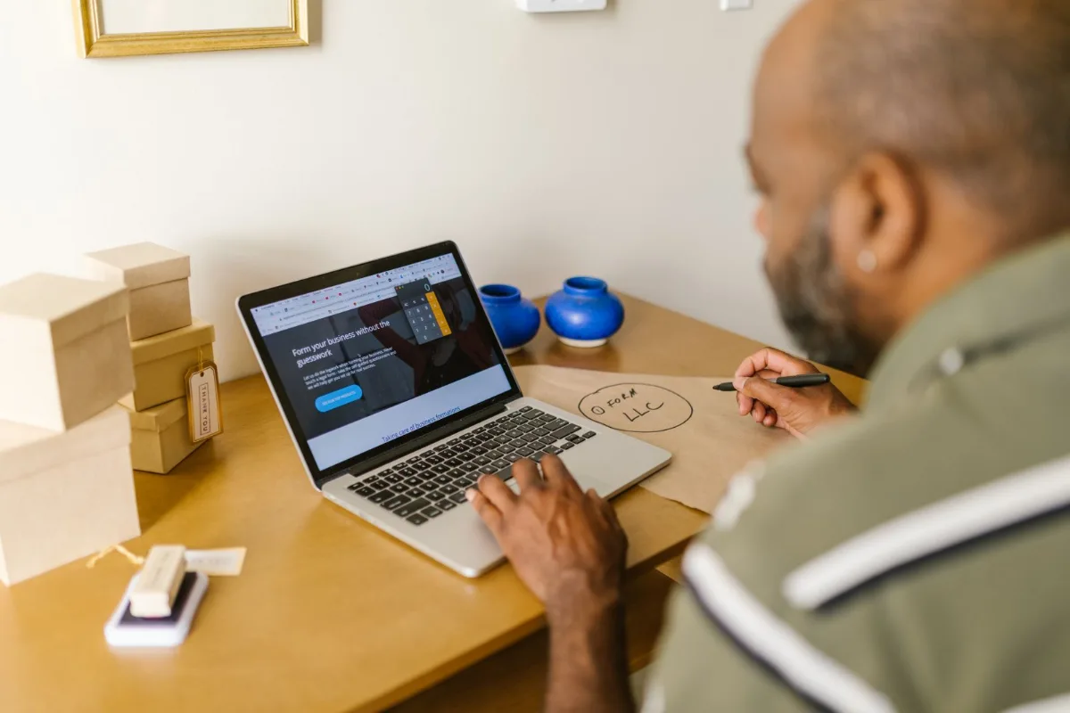 A service business owner at a kitchen table looking at a customer list exported to a spreadsheet on a laptop