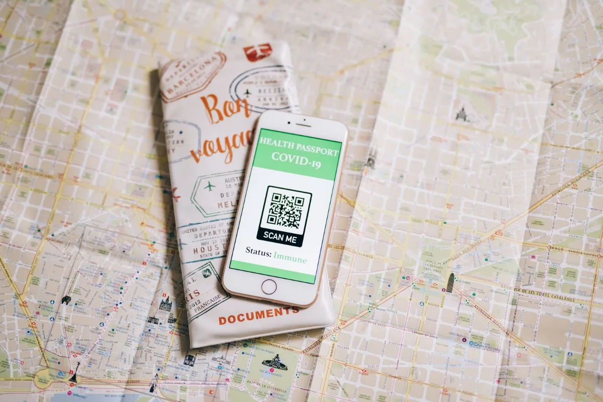 A direct mail postcard with a QR code held next to a phone showing the tagged landing page URL
