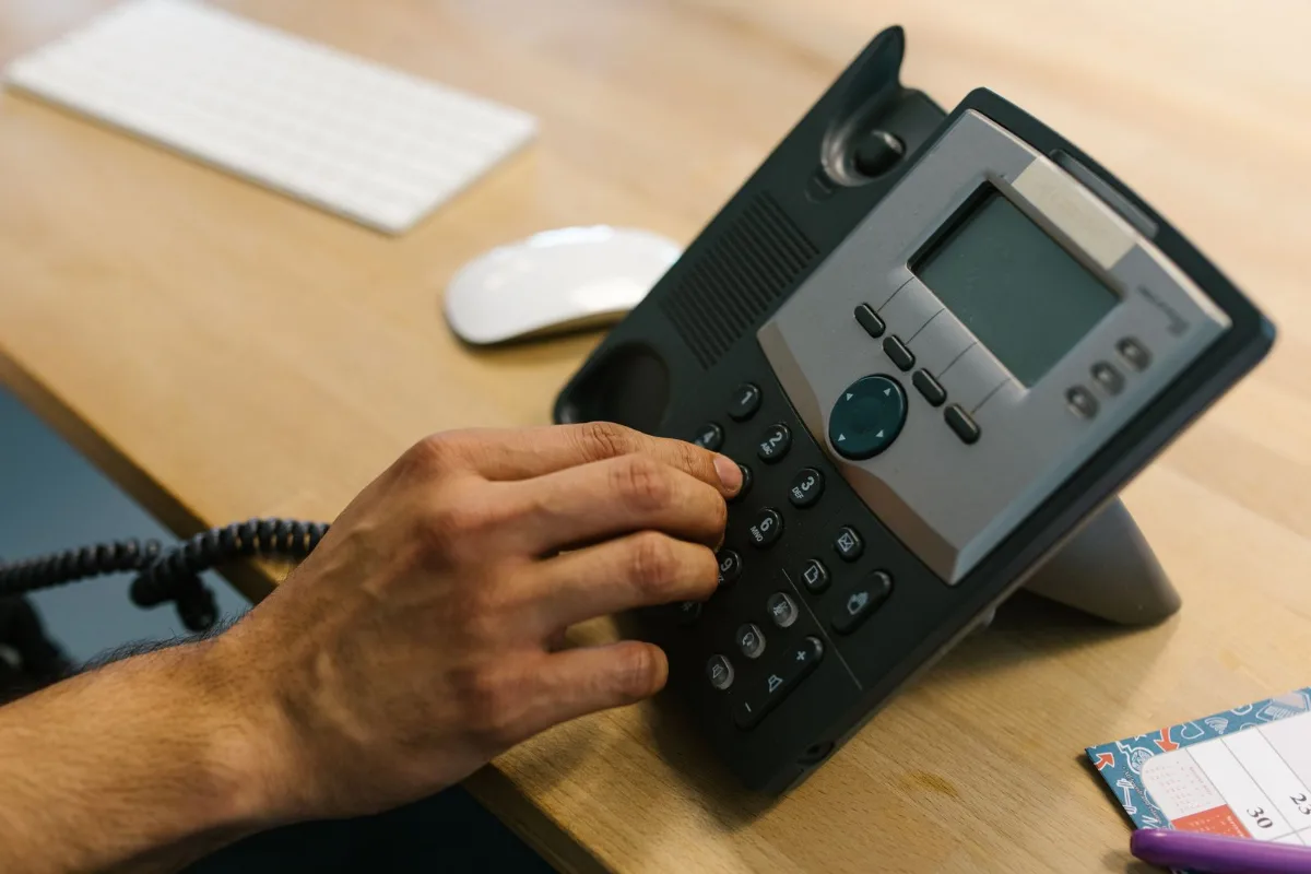 A phone ringing unanswered on a service counter with a whiteboard job list behind it