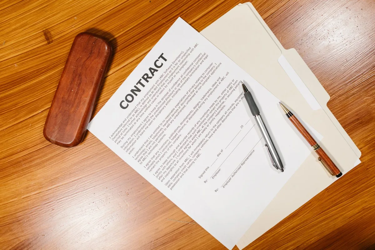 Business owner comparing a printed marketing contract against a laptop showing account access settings