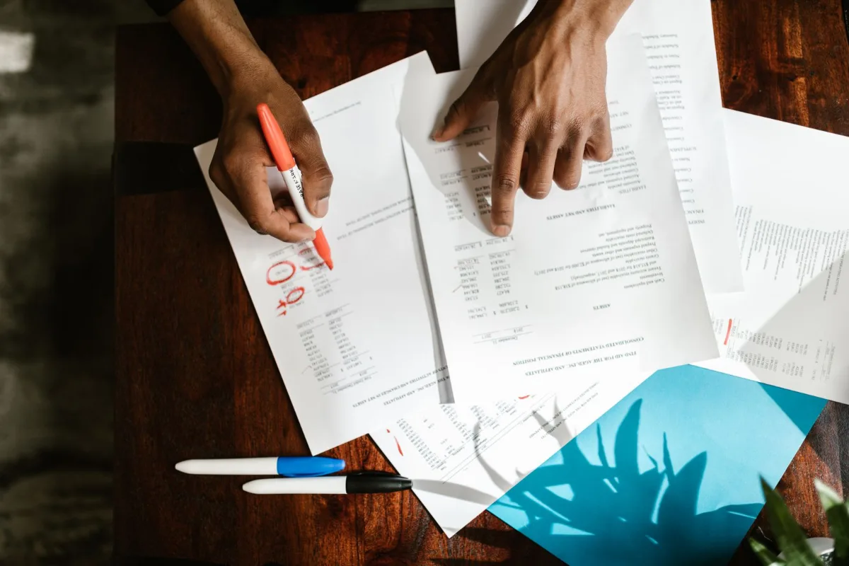 A two-page website proposal and a twelve-page proposal side by side on a contractor's desk with pricing lines highlighted